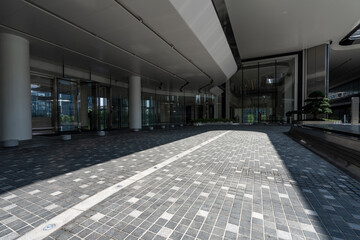 Obraz premium Modern building entrance corridor with geometric pavement and strong shadows