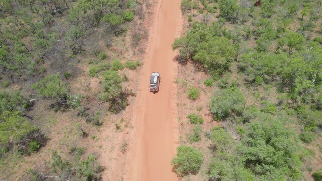 Aerial View of White 4WD Driving on Red Dirt Track Through Sparse Bushland, Australian Outback