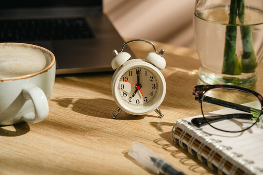 Time management concept with alarm clock, laptop and coffee on home office desk, workspace