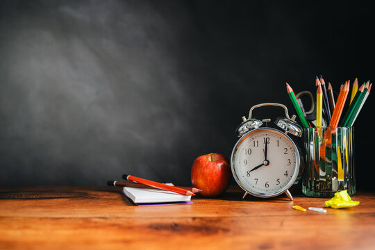 School stationery and alarm clock on classroom desk, education banner