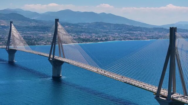 An aerial view of the long suspension bridge spanning deep blue water showcasing impressive structural engineering and traffic flow.