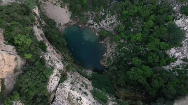 Large limestone cliffs overlooking turquoise water of landmark Swaik Lake in Punjab, Pakistan. Descending Aerial Shot.