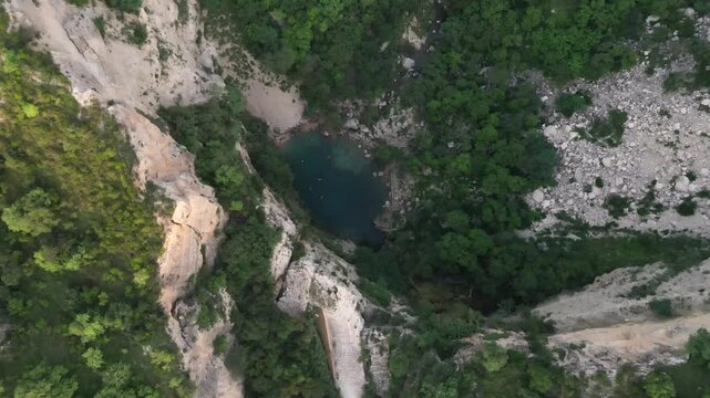 Swaik Lake's turquoise waters and rugged limestone cliffs as swimmers enjoy the scenic Punjab landscape, Pakistan.