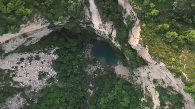 Rising aerial shot of landscape and limestone cliffs surrounding pristine Swaik Lake in Punjab, Pakistan.