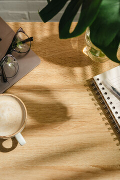 Home office workspace with open notebook, coffee and eyeglasses on wooden desk, top view with copy space