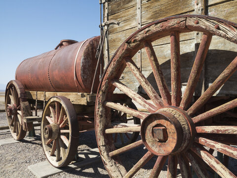 View of a historic wooden borax wagon with a large rusted metal water tank in Death Valley National Park, Death Valley, California, United States.