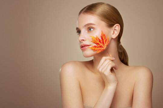 Portrait of beautiful young woman with autumn leafs. Healthy clean fresh skin natural make up beauty eyes
