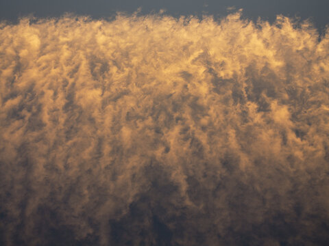 View of golden hour clouds illuminated by the setting sun over Death Valley National Park in Death Valley, California, United States.