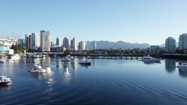 Drone flying over water and boats in Vancouvers false creek on sunny day