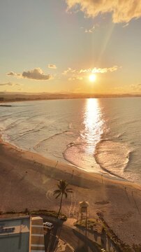 Sunset light across Coolangatta beach and Greenmount headland, aerial drone footage, Queensland Australia - vertical video
