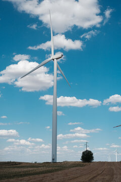 View of a wind turbine at the Wind farm Alibunar set against a bright blue sky with scattered white clouds in a rural field in Alibunar, Vojvodina, Serbia.