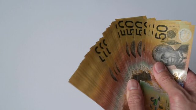 Saving money investment and financial planning concept. A man counting hundred and fifty Australian dollar bills in cash on hand as payment, savings, business funds, dividends, wealth.
