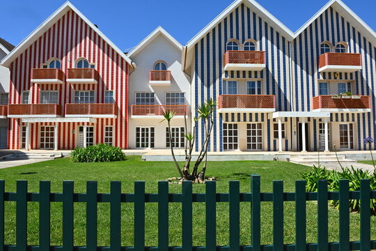 View of Costa Nova do Prado featuring iconic colorful striped houses with balconies and a green lawn in the foreground, Gafanha da Encarnacao, Aveiro, Portugal.