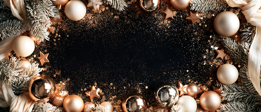 Black velvet mockup with Christmas ornament, shimmer, artificial snow and pine branches arranged around clear copy space. Flat lay composition for Christmas and New Year backgrounds and advertising.