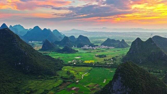 Aerial drone view of sunset over karst mountain peaks and rural farmland in Guilin, China.