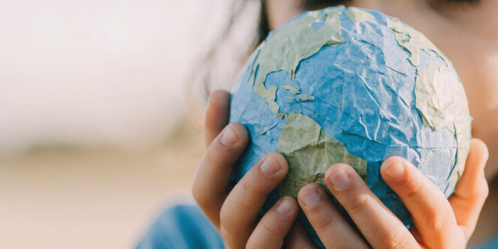 Global warming and changes in climate and the environment with a child hands holding a paper model of the world