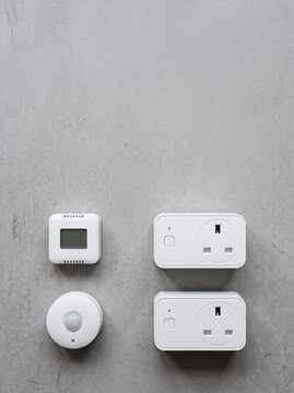White Smart Home Plugs And Sensors On Concrete Background