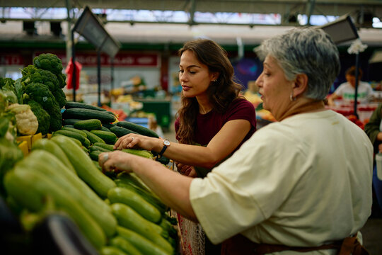 Women choosing fresh produce at local market stall