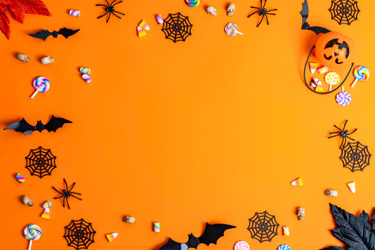 Halloween border with candy bats spiders on orange background