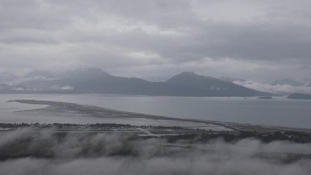 View of Homer Spit extending into Kachemak Bay under a cloudy sky in Homer, Alaska, United States.