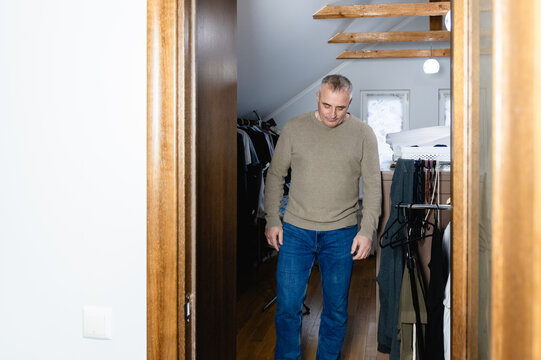 Man walks through a doorway into a room with clothes and storage