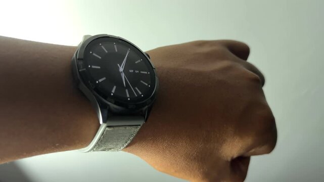 Point of view (POV) close-up shot of a person raising their wrist to check the time on a modern round smartwatch