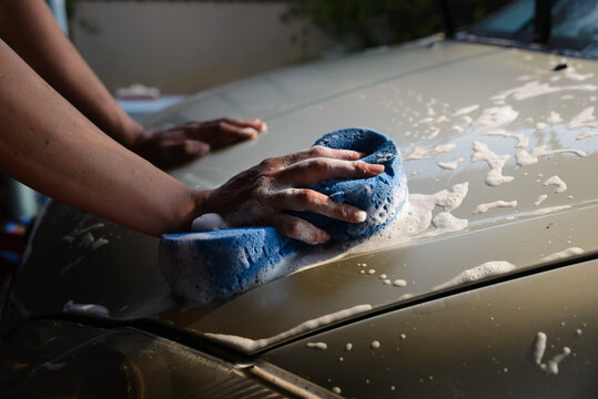 Car cleaning with sponge and soap, hand washing vehicle exterior for car wash, auto care and maintenance, showing foam and suds on automotive surface during manual cleaning.