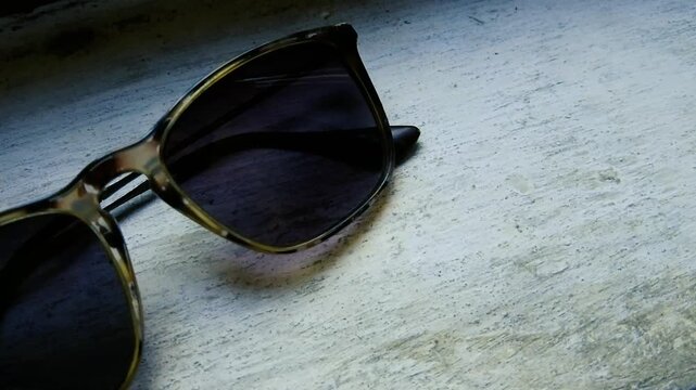 Tortoiseshell sunglasses resting on rustic weathered white wooden surface closeup