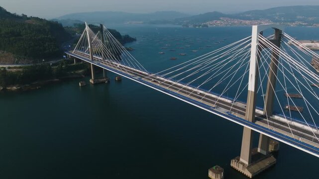 Stunning aerial perspective of the Rande Bridge near the city of Vigo in northern Spain, showcasing the powerful, geometric symmetry of its cable-stayed design spanning the deep blue, tranquil estuary