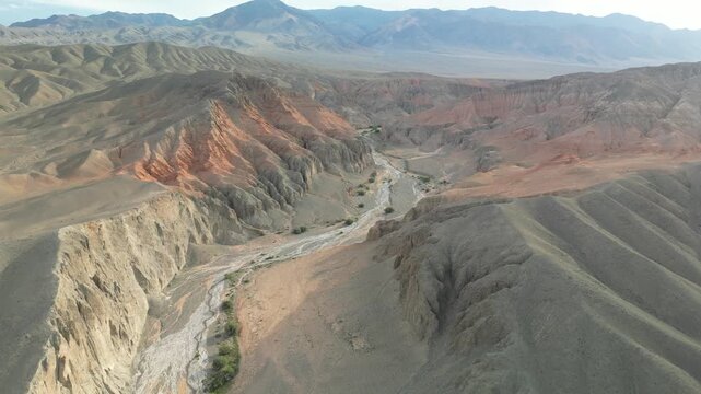High altitude top down aerial drone shot flying over a dry river bed inside a red rock canyon resembling a martian landscape, flat log profile