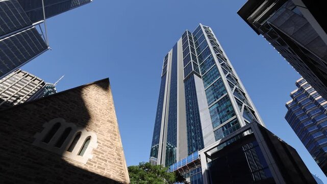 View of St George's Cathedral with modern skyscrapers in the background under a clear blue sky in Perth, Western Australia, Australia.