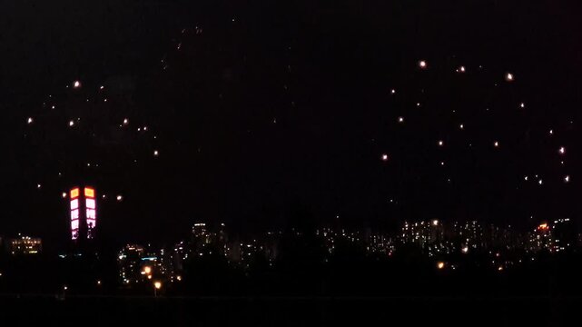 Overlapping fireworks shells blooming in magenta, gold and red over the Seoul city skyline at night, above the Han River in South Korea