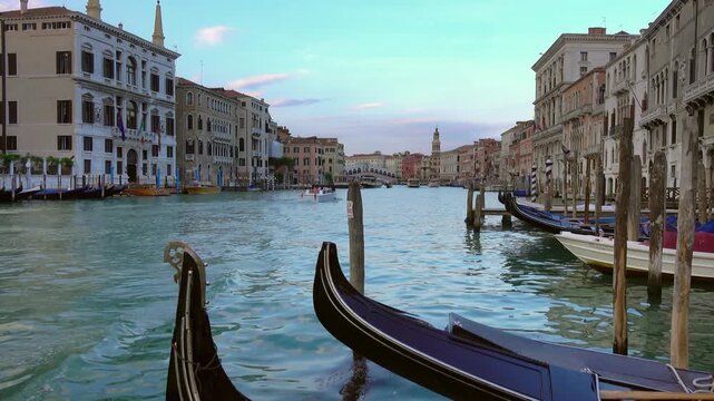 View of the Grand Canal in Venice with traditional gondolas moored along the historic buildings and a boat cruising on the water in Venice, Veneto, Italy.