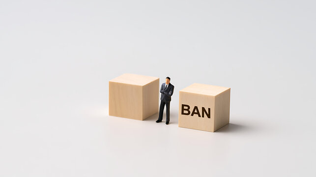 Miniature businessman figure stand between wooden block with text ban on white background, corporate restriction and regulation concept