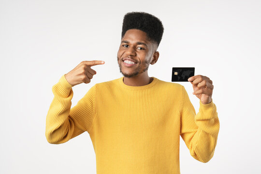 African American customer holding credit card and pointing with finger isolated over white background, smiling young man presenting bank card, online payment, shopping, banking and finance concept