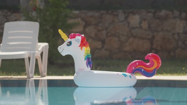 Pool with unicorn float and chair in sunny backyard during summer afternoon