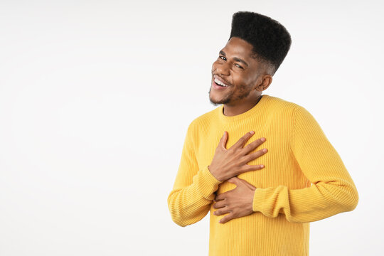 Grateful African man holding hands on chest near heart isolated over white background, emotional young male expressing gratitude, appreciation, sincerity, kindness and heartfelt thankfulness concept