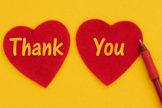 Thank you message with 2 red hearts and a pen on bright yellow felt