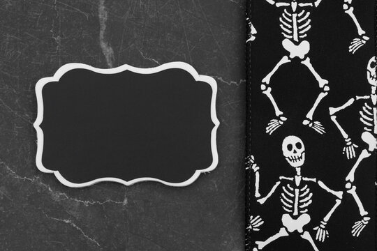 Halloween with skeletons border with blank chalkboard on black marble for celebration events