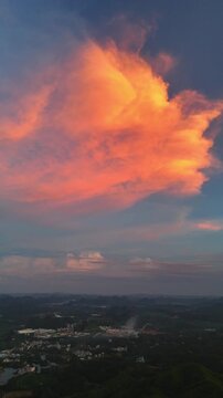 Vertical Video: Massive orange-red sunset cloud above the silhouette of a karst mountain village