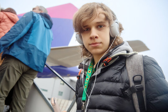 Teenager traveling with headphones boarding an airplane