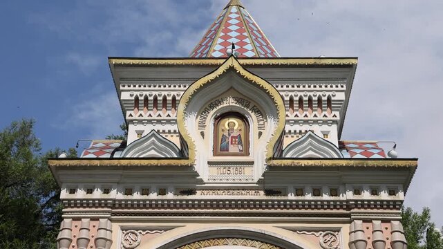 View of the ornate Tsesarevich Nicholas Arch featuring traditional Russian architectural details, colorful roof tiles, and a central religious icon in Vladivostok, Primorsky Krai, Russia.