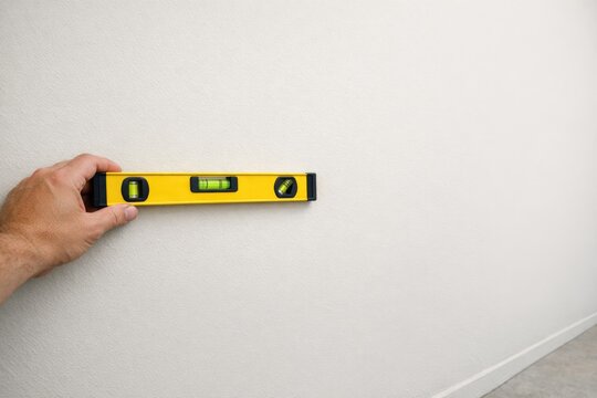 A person holding a spirit level tool in their hand, possibly for construction or DIY projects