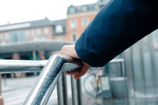 a man grips a rain-covered railing in Copenhagen