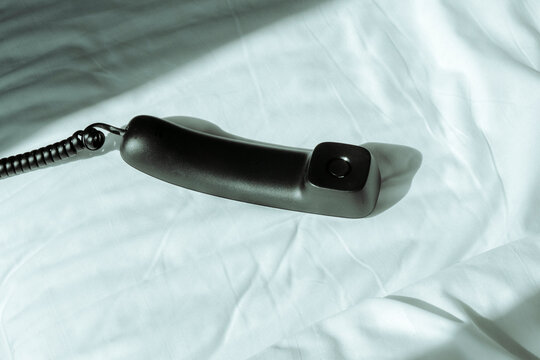 a landline telephone handset on an unmade bed
