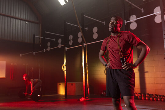 Diverse gym members pausing and deadlifting barbell at gym in red shirt, copy space