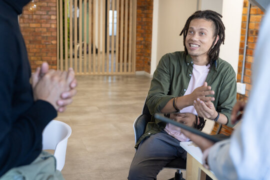Diverse coworkers discussing and gesturing in office with tablet and swivel chair, copy space