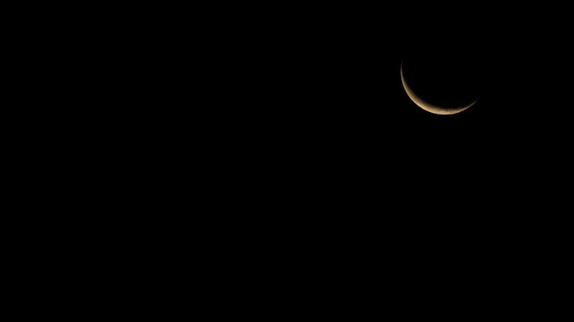 10% waning crescent Moon rises through the dark sky at 4:30 AM EDT, appearing dim and warm amber through near-horizon atmospheric haze.
