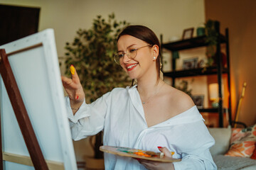 Smiling woman painting on canvas in home studio © Dusan