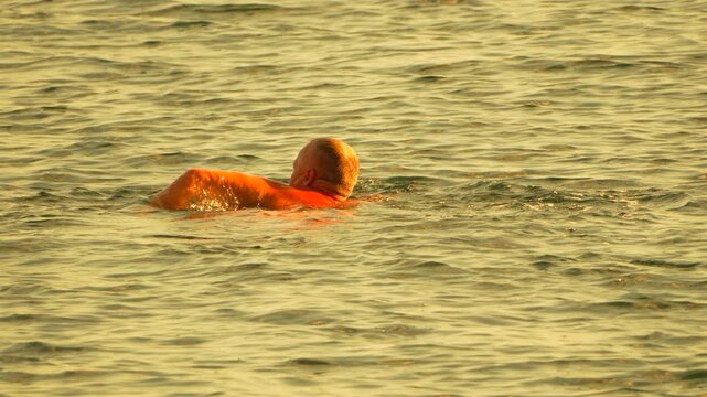 Swimming man, water, freestyle in golden ocean during golden hour